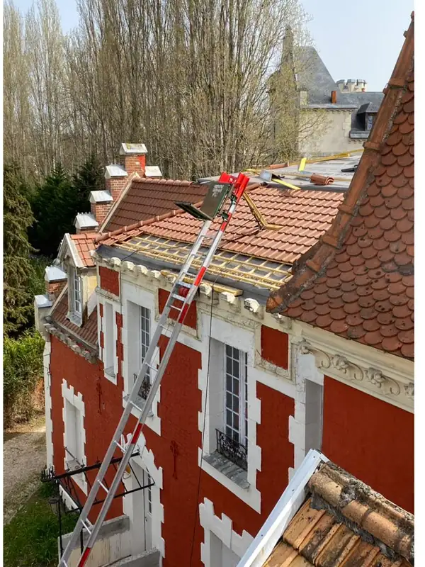 Couvreur MCT et monte-matériaux sur le chantier de couverture d'une maison en briques à tourelle